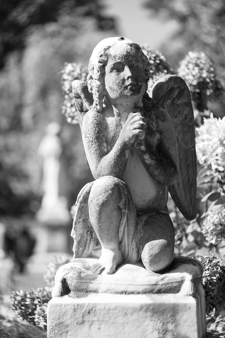 Sculpture of a child angel kneeling and praying at Oakland Cemetery in Atlanta